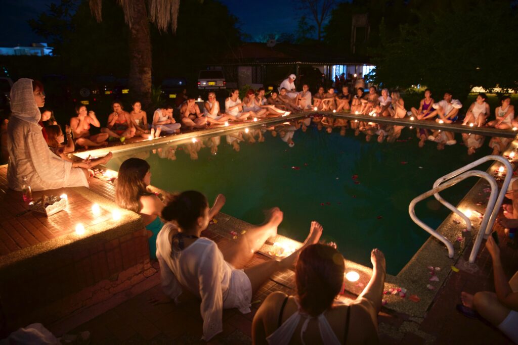 Personas reunidas al rededor de una piscina meditando