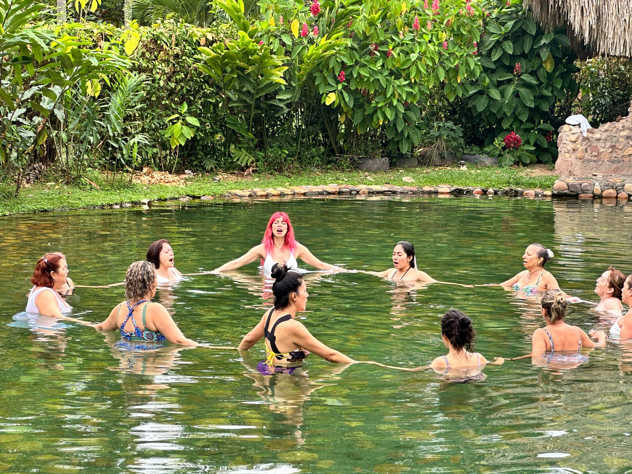 Grupo de personas en una piscina natural realizando una ceremonia espiritual en cosmogénesis en restrepo meta colombia