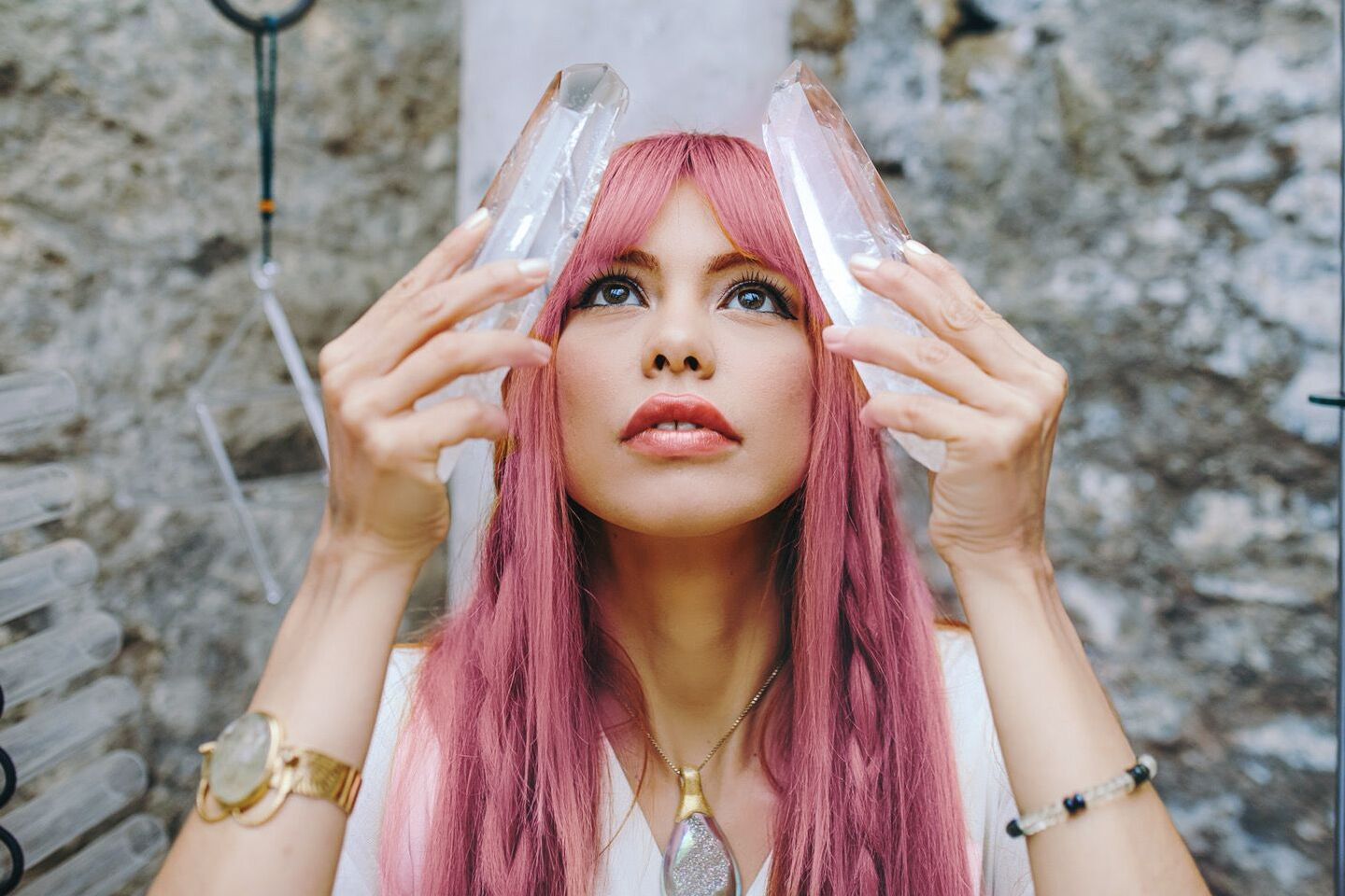 Mujer de cabello con 2 torres de cuaezo transparente cada una en una mano elevándolas sobre su cabeza y mirando hacia el cielo