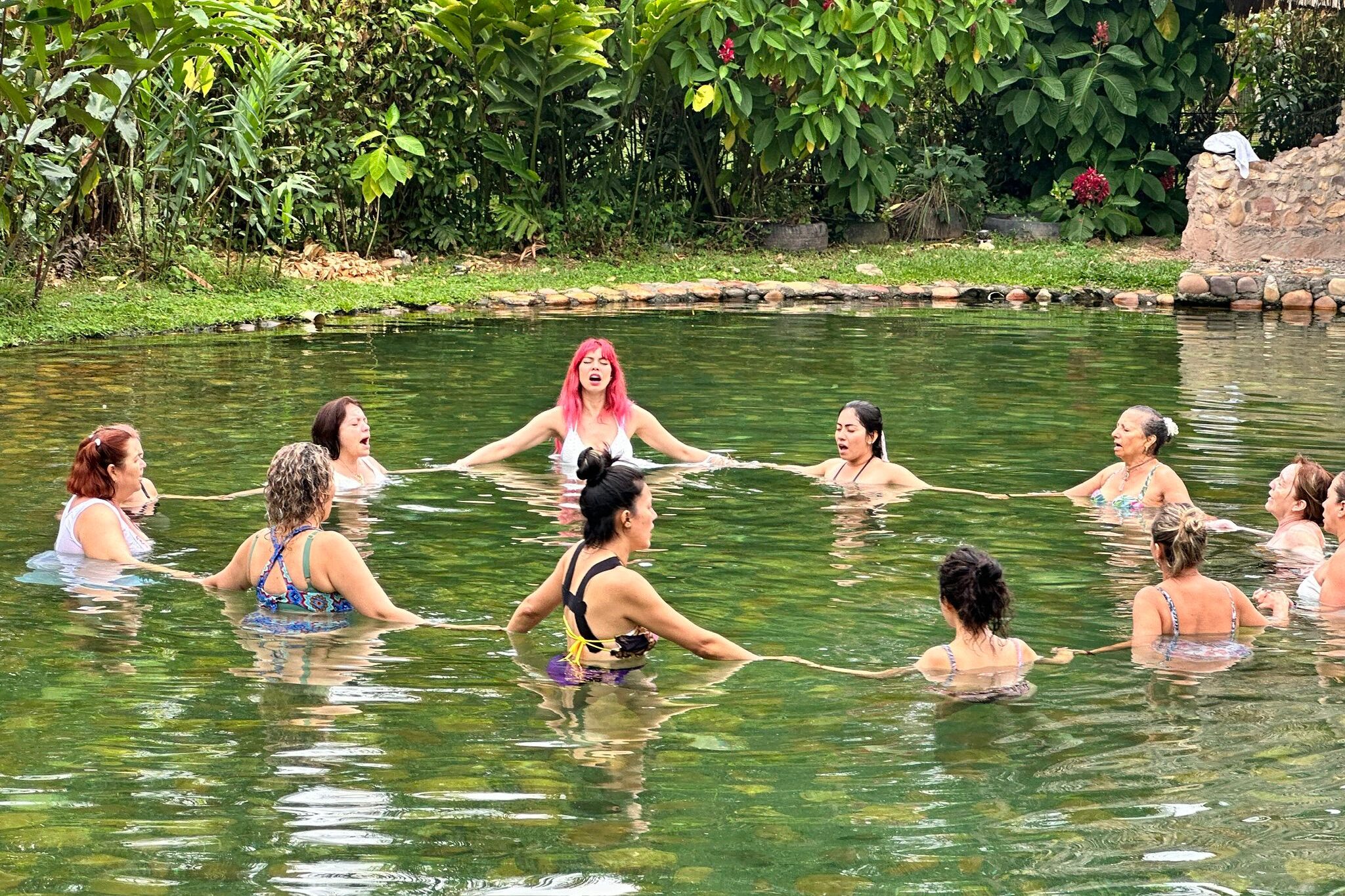 Grupo de personas en una piscina natural realizando una ceremonia espiritual en cosmogénesis en restrepo meta colombia